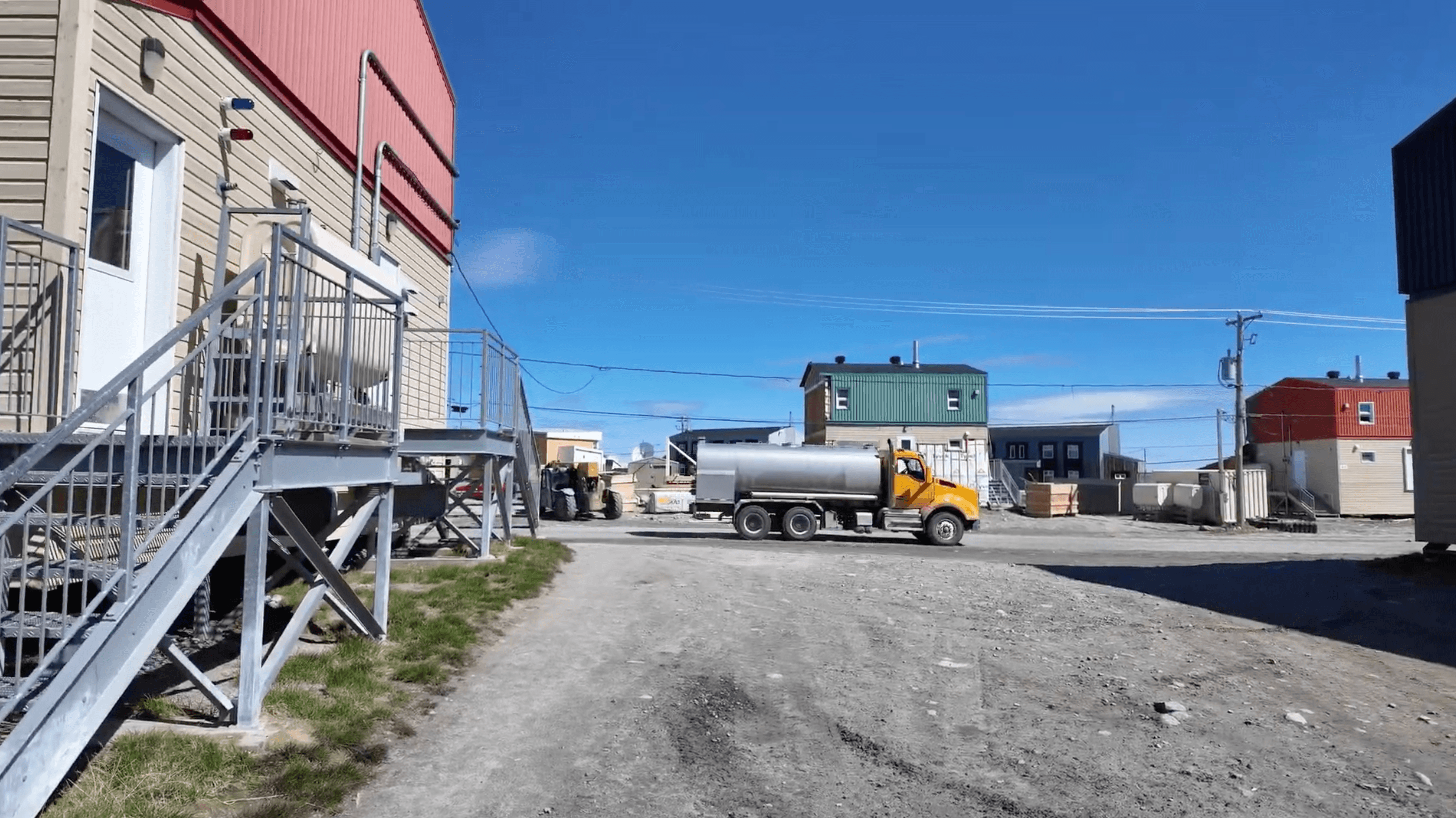 Water truck passing houses on a Puvirnituq road