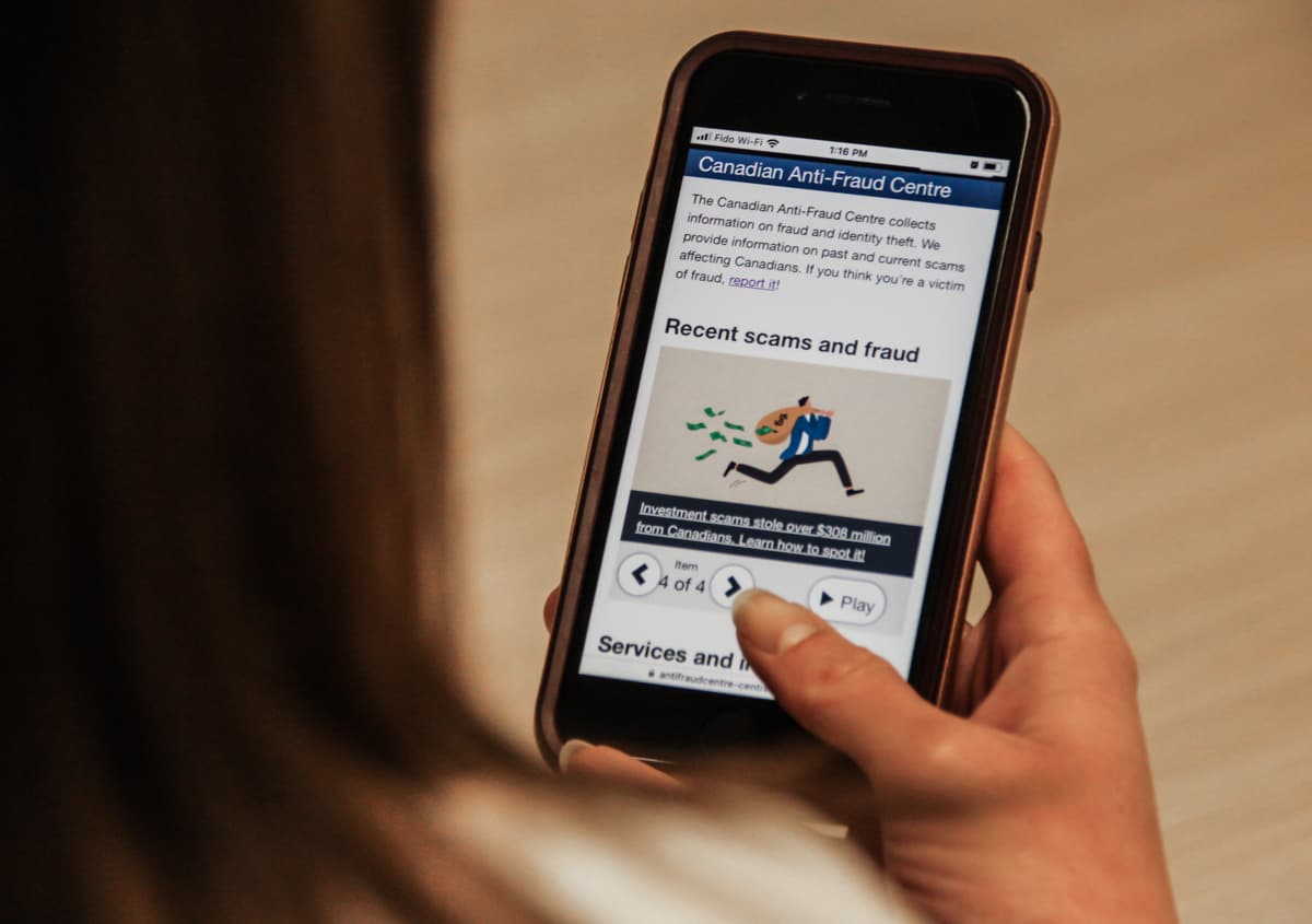 woman looking at canadian anti fraud center website on phone